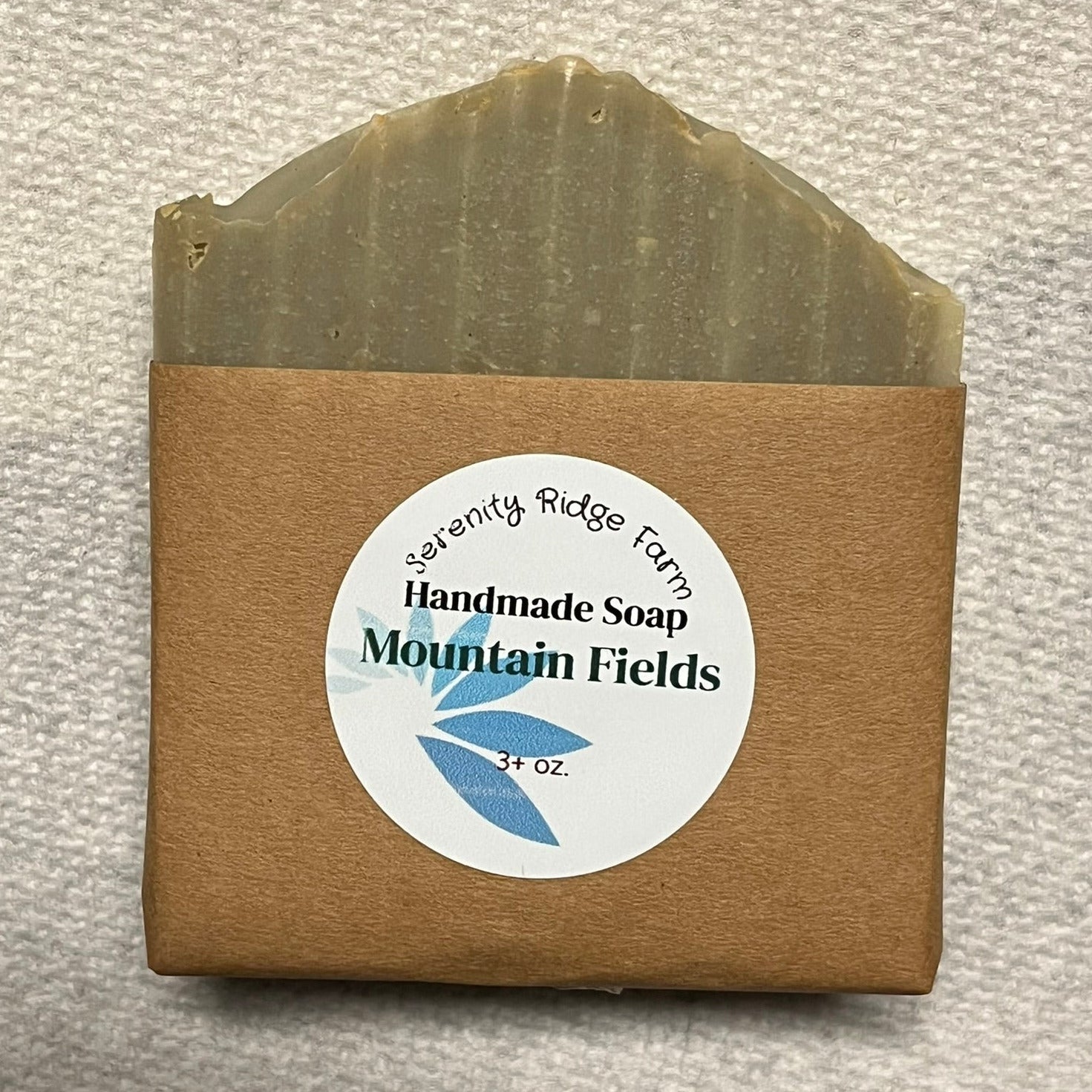 Handmade soap bar with a brown packaging label on a textured gray background