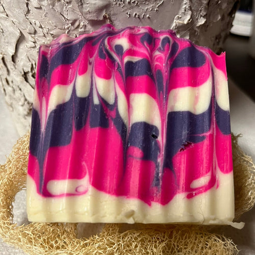 Colorful soap bar with pink and purple swirls on a textured surface