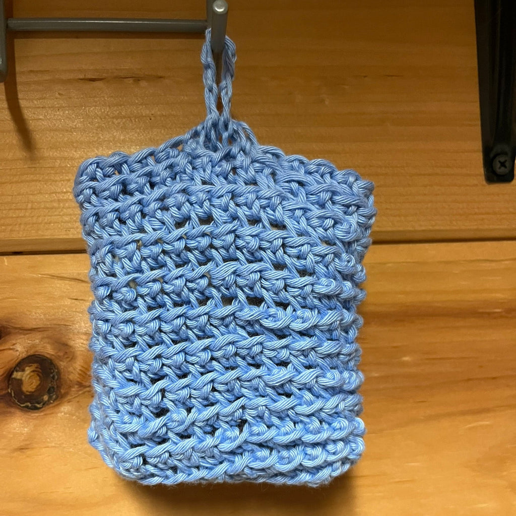 Blue crochet soap pouch hanging from hook.