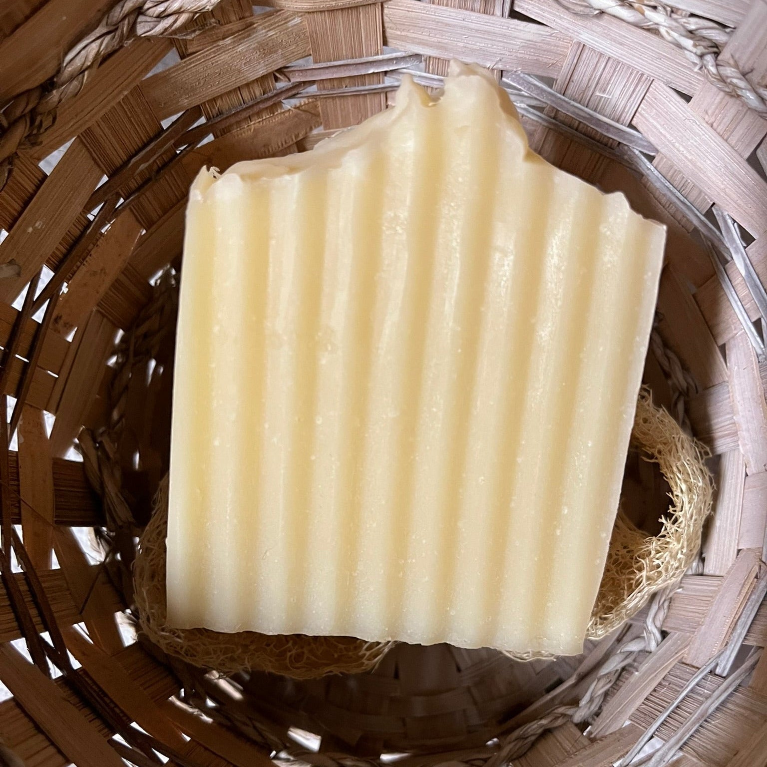 Bar of soap on a wooden surface with a woven basket